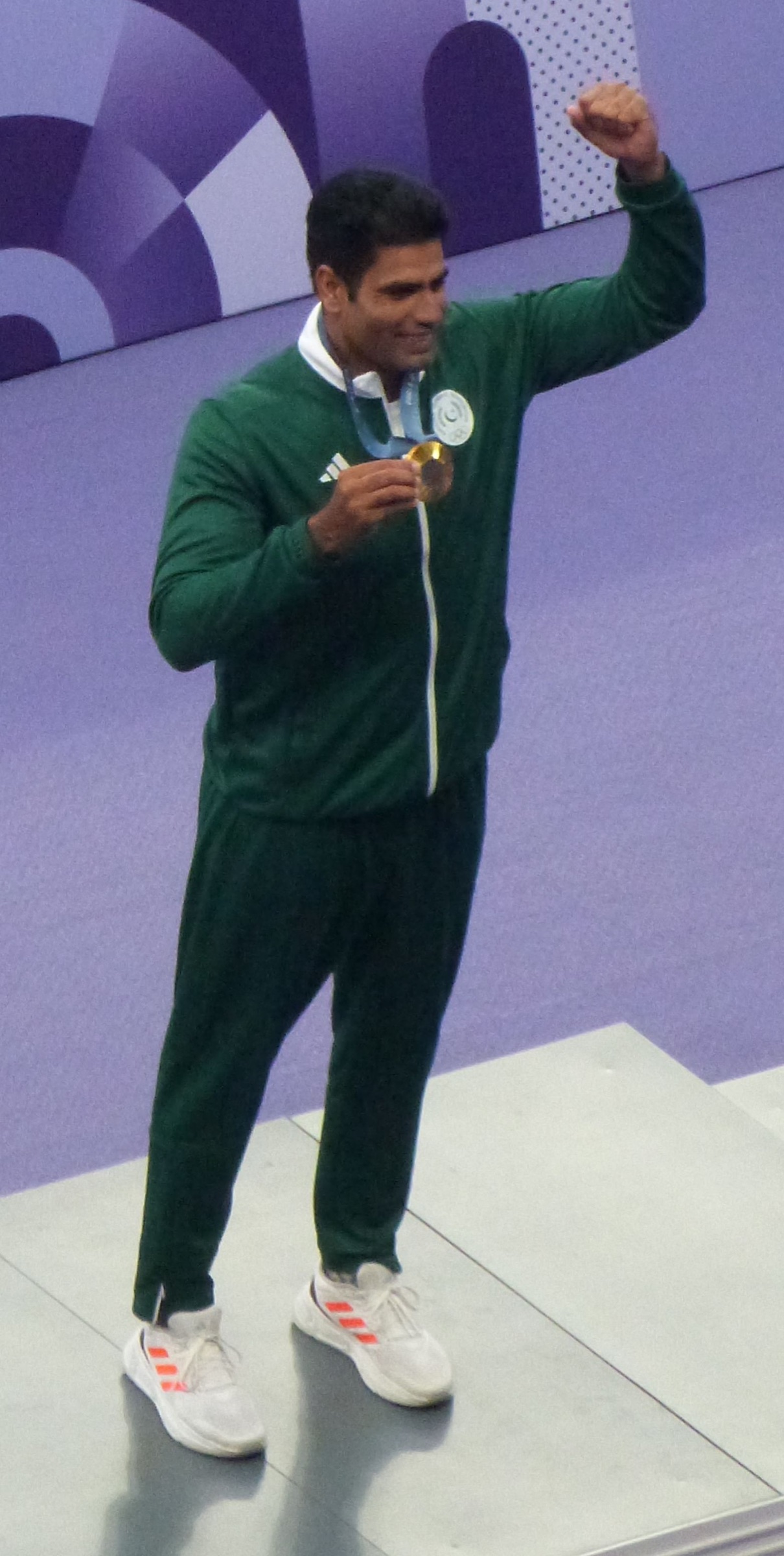 Arshad Nadeem holding his Olympic gold medal on the Paris podium.