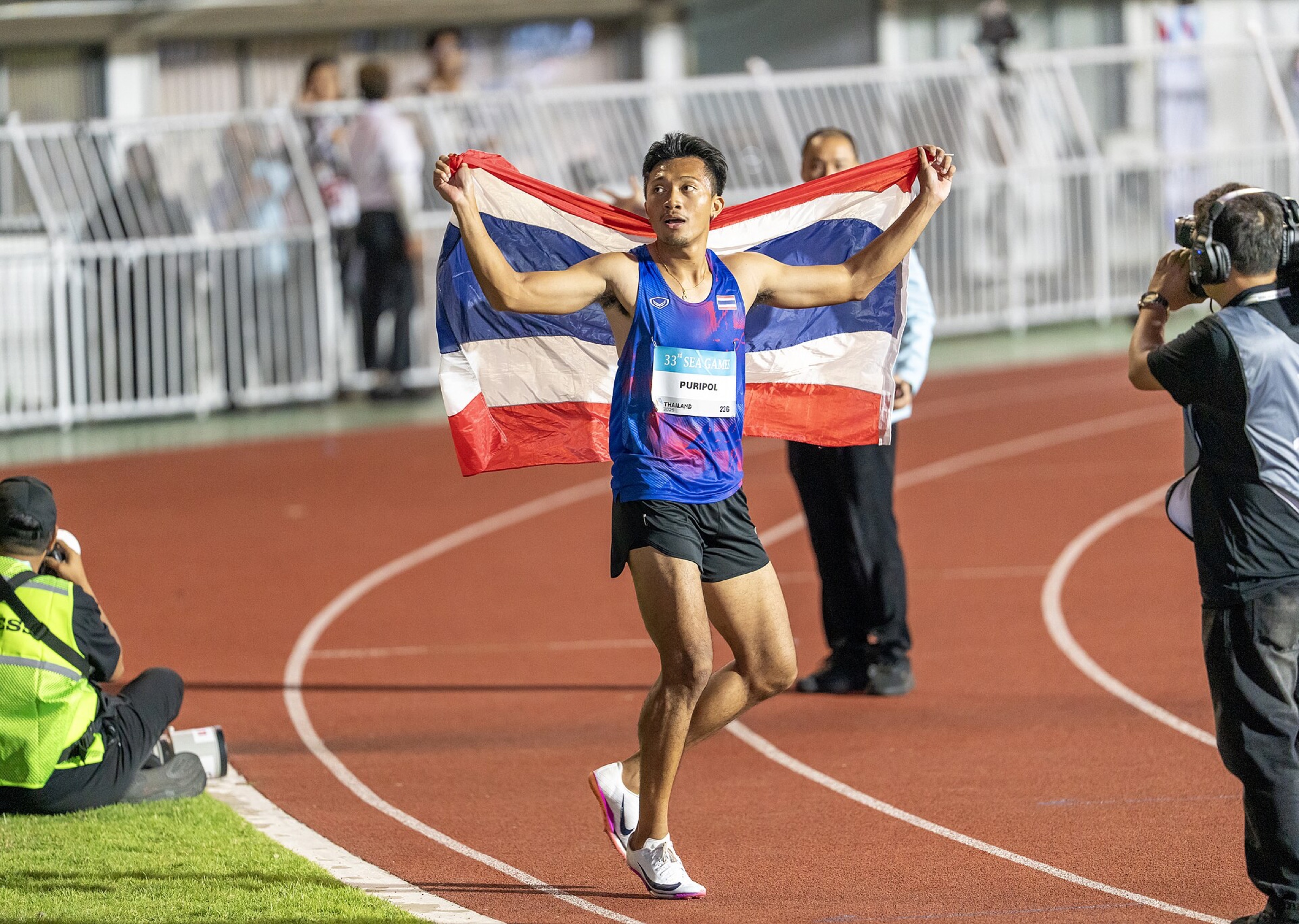 Puripol Boonson holding the Thai flag after a 2025 sprint.